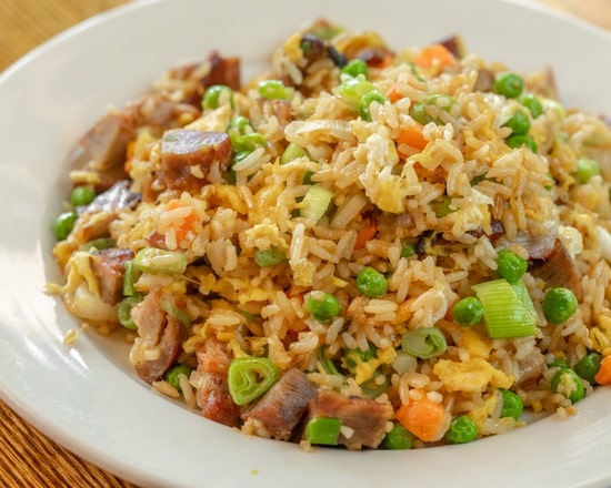 BBQ pork fried rice with egg, peas and scallion on a white plate